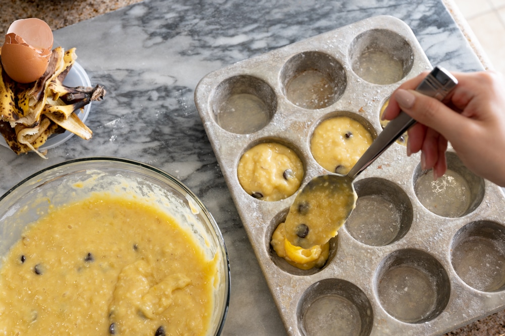 Banana bread mix being filled into cupcake tins